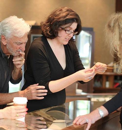 Zoey showing a piece of jewelry while Chai and Joy look on