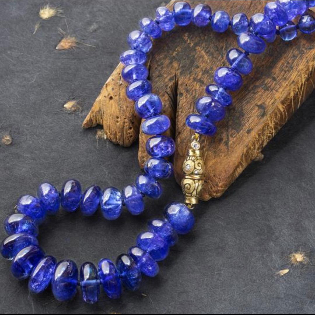 Purple tanzanite beaded necklace with gold clasp on a piece of driftwood