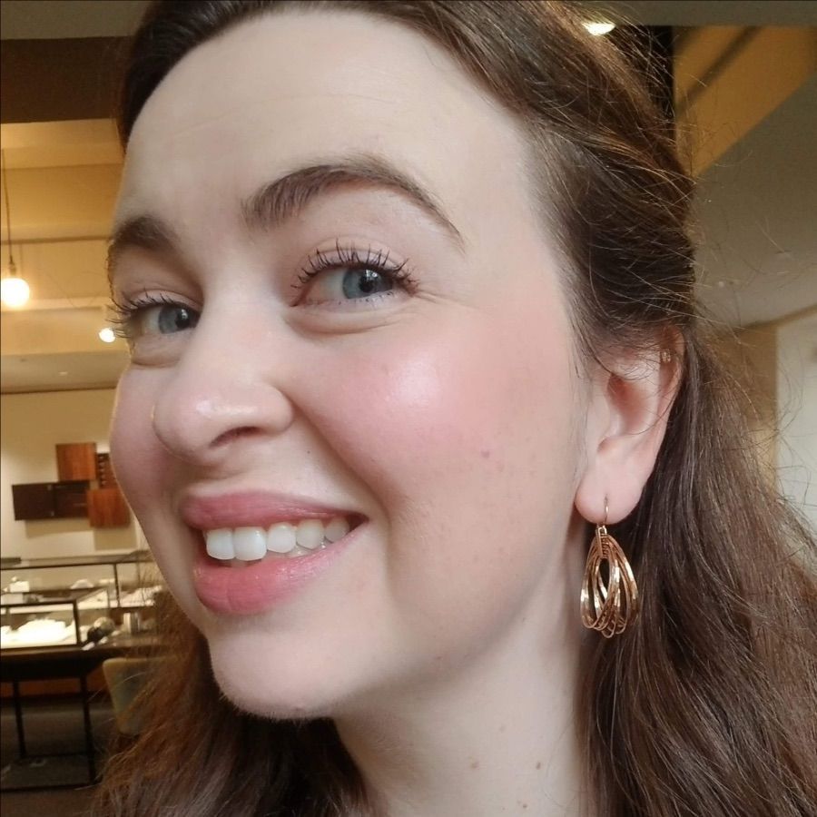 Close up of woman's face wearing gold round dangle earrings