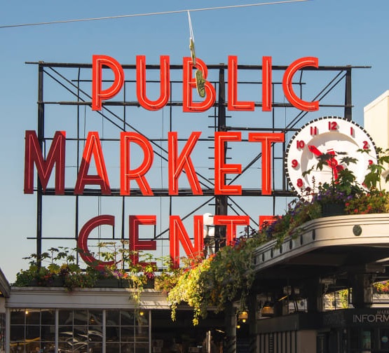 Link takes you to information about Pike Place Market Foundation Covid Update page. Image shows Public Market Center sign at Pike Place Market