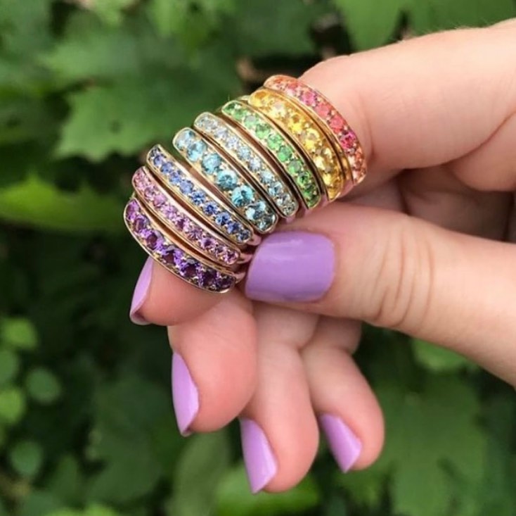 link takes you to see Jane Taylor Jewelry. Image shows stack of rings creating a rainbow on index finger