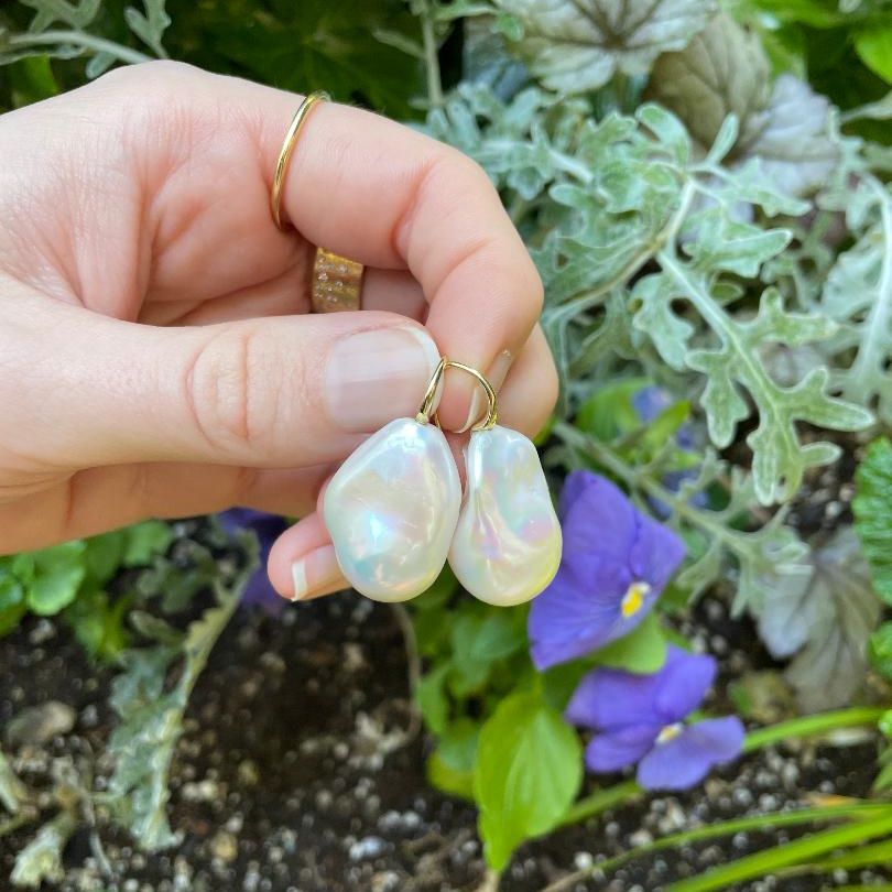hand holding a pair of oblong shaped pearl earrings