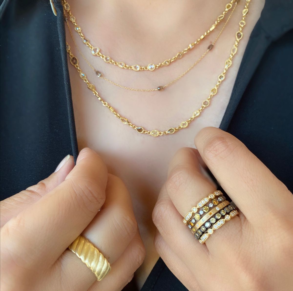 woman's neck and hands showing off rings and necklaces