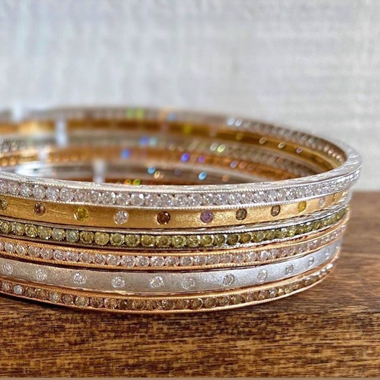 stack of bangle bracelets in yellow, white and rose gold with multicolored diamonds