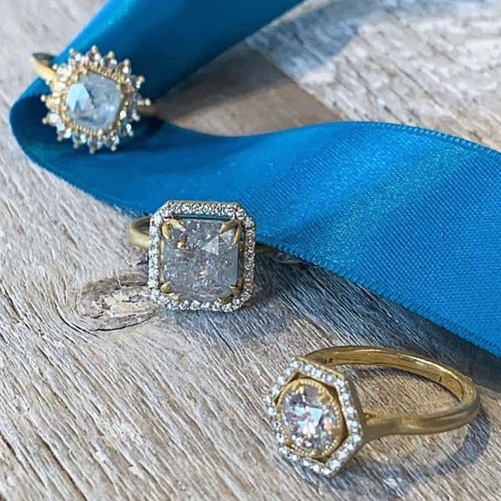 3 rough diamond rings on wood background with blue ribbon