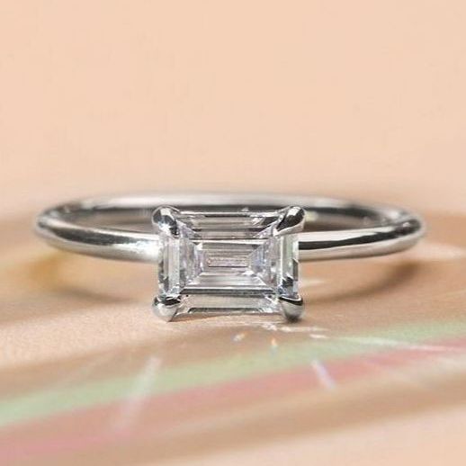 emerald cut diamond ring in white gold on a peach background