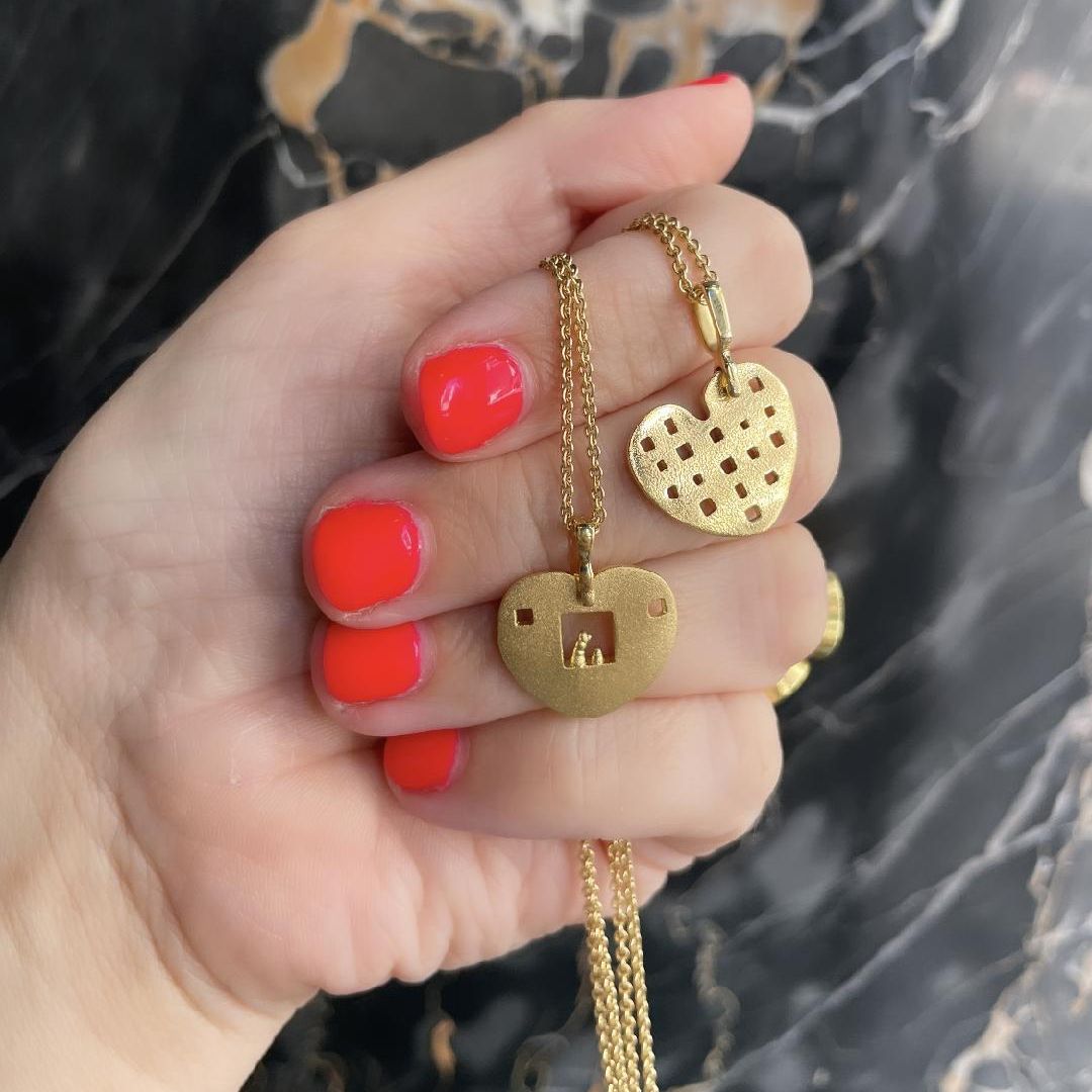 Woman holding two necklaces by jewelry designer Alex Sepkus. 18K Gold "Heart" Pendant Necklaces with 18-inch cable chains.