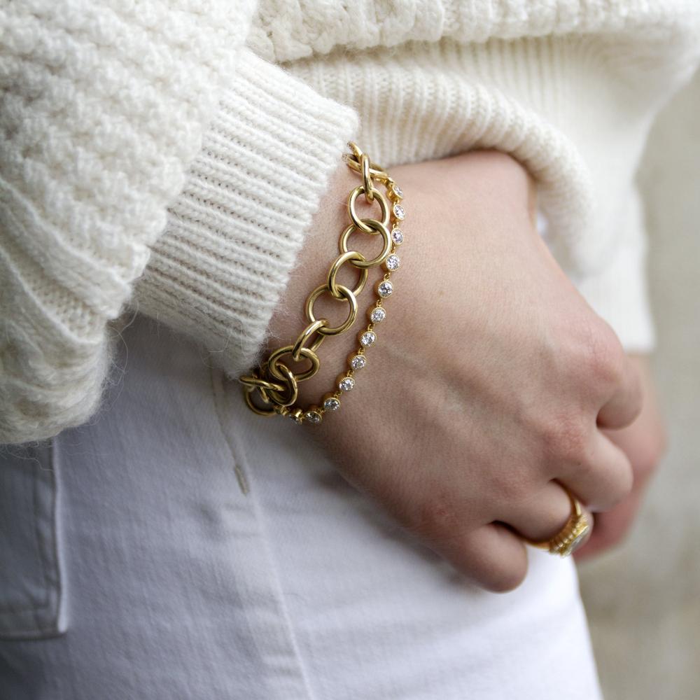 white sweater with 2 gold bracelets on wrist
