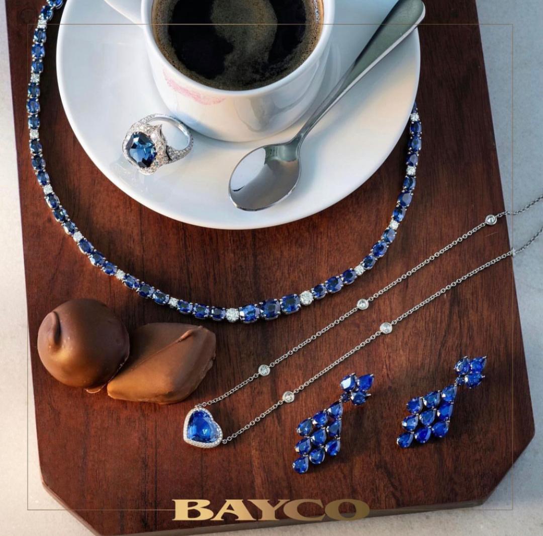 Birds eye photo of a coffee cup with blue sapphire jewelry all around.