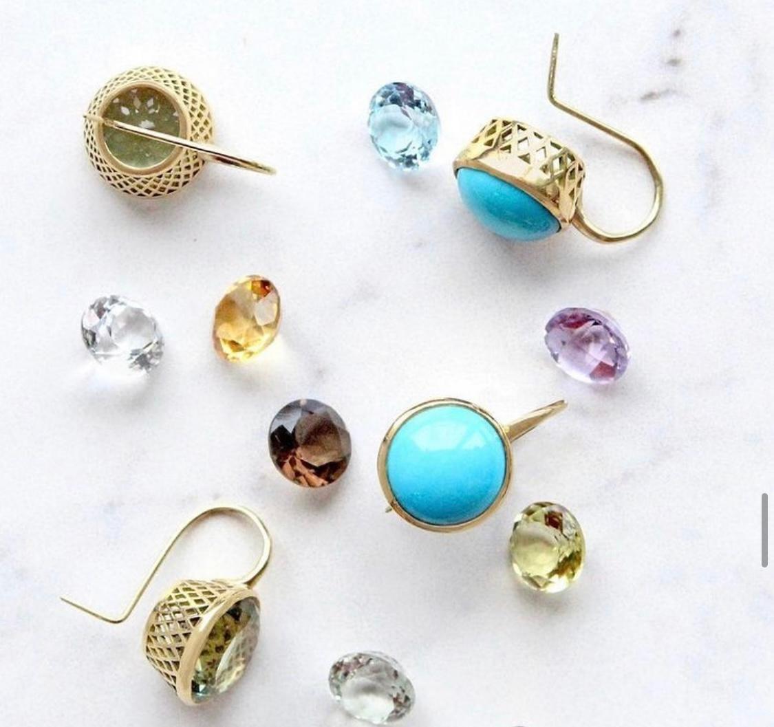 Gold earrings with gemstones scattered around them 