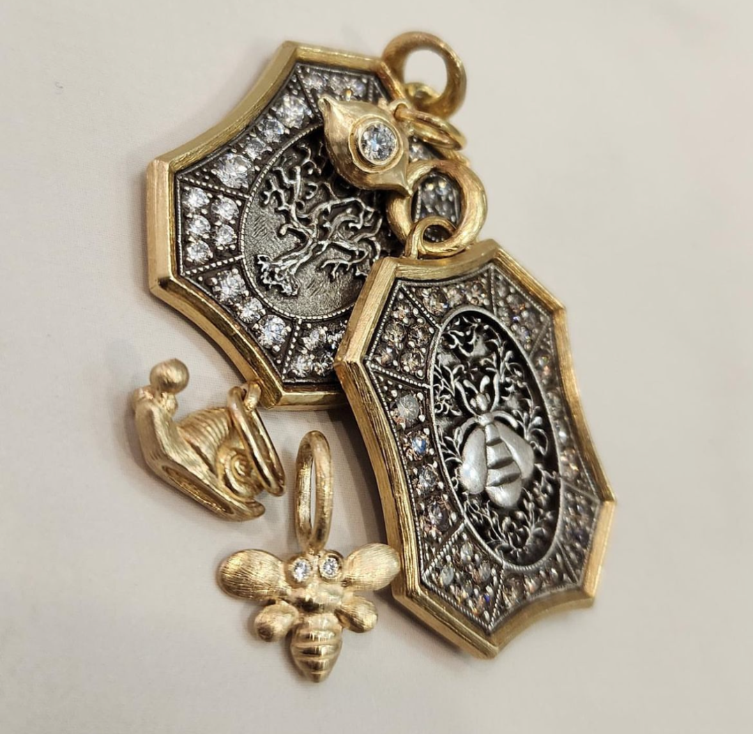 4 silver and gold and diamond charms on a whitish background