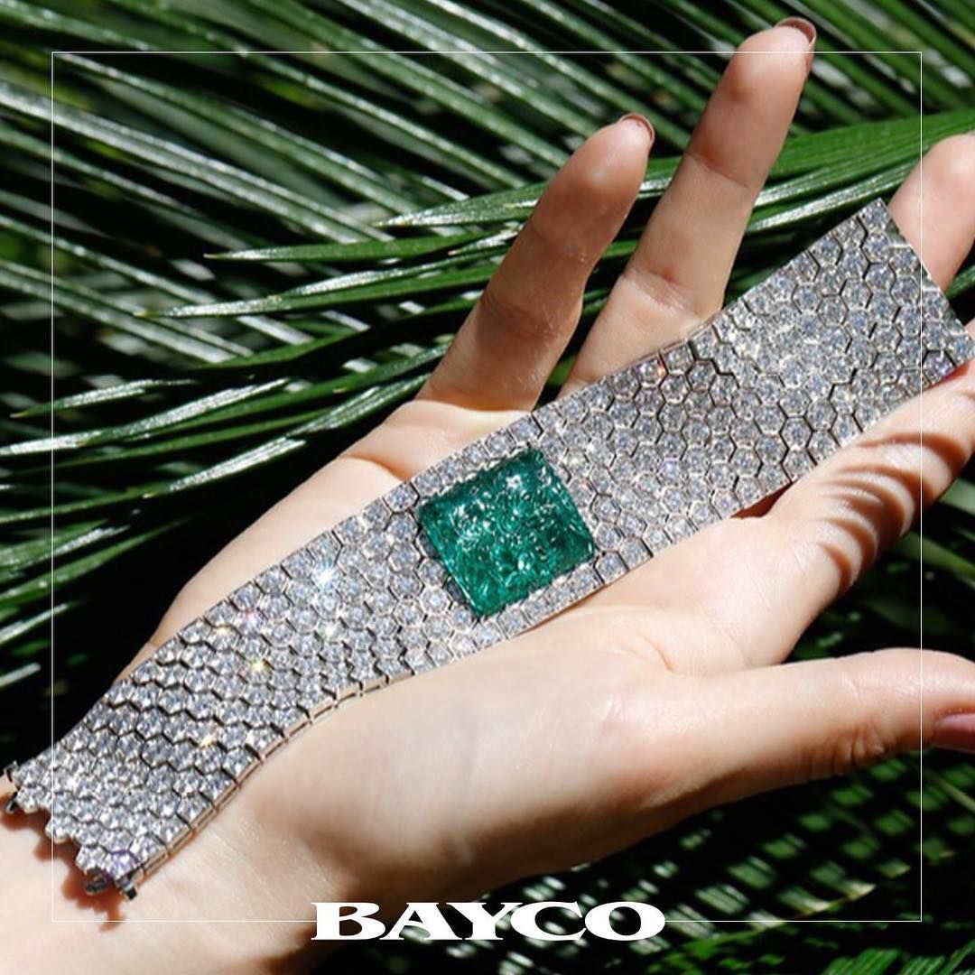Emerald and diamond bracelet on a hand with a leaf background