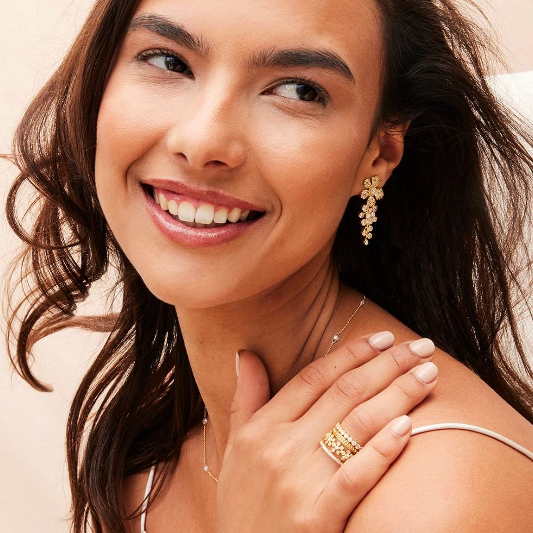 woman smiling with earrings, rings and necklace on