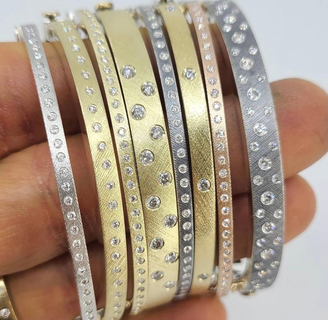 multiple bangle bracelets in gold and silver with diamonds being held 