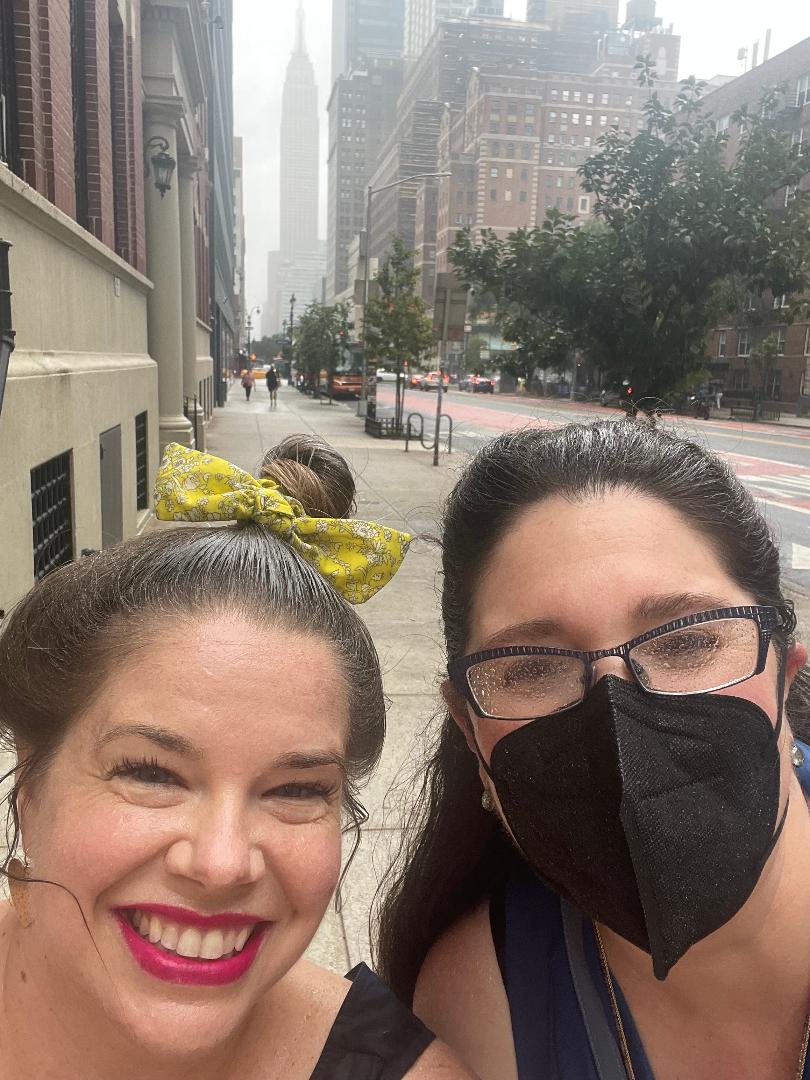 photo of two women in the rain with the empire state building in the background