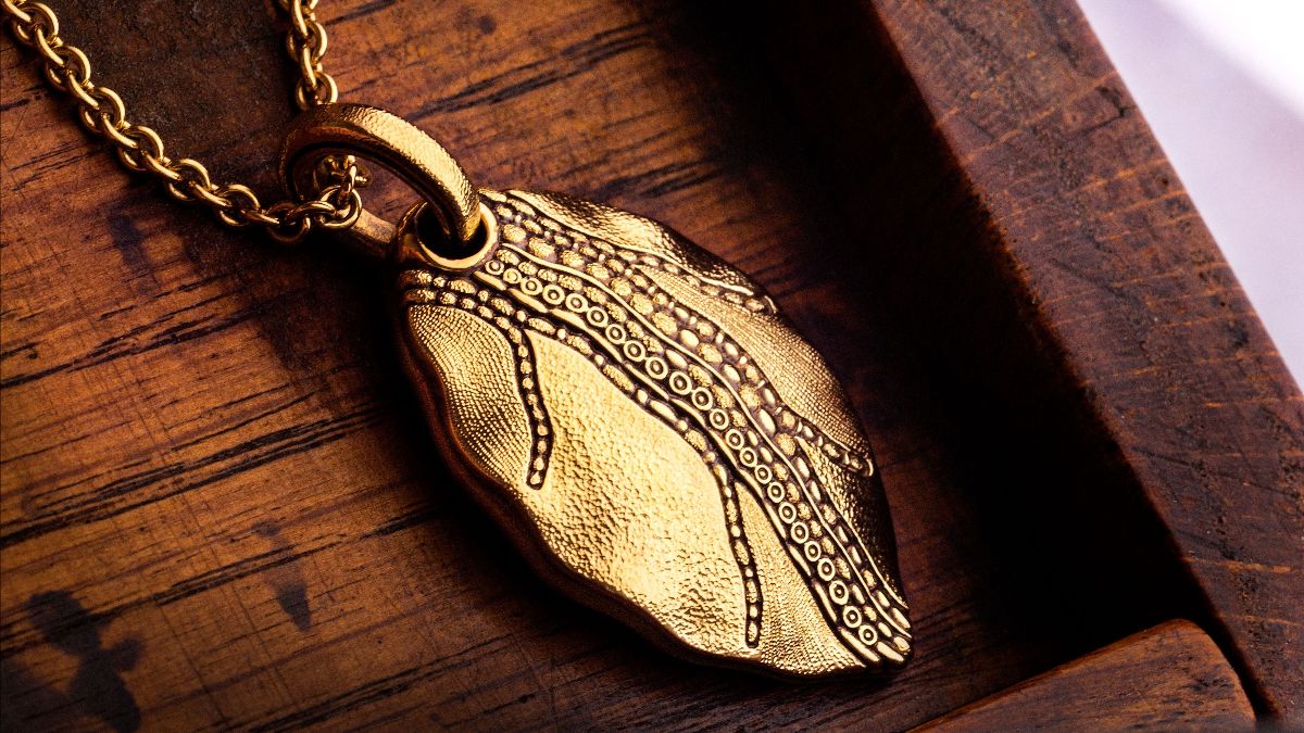 yellow gold leaf necklace on wood background