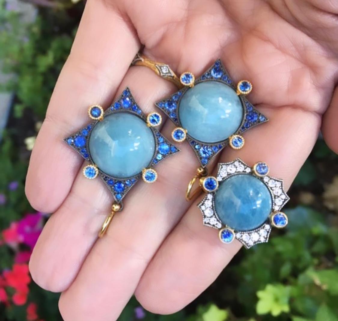 Aquamarine and sapphire earrings and ring on a hand