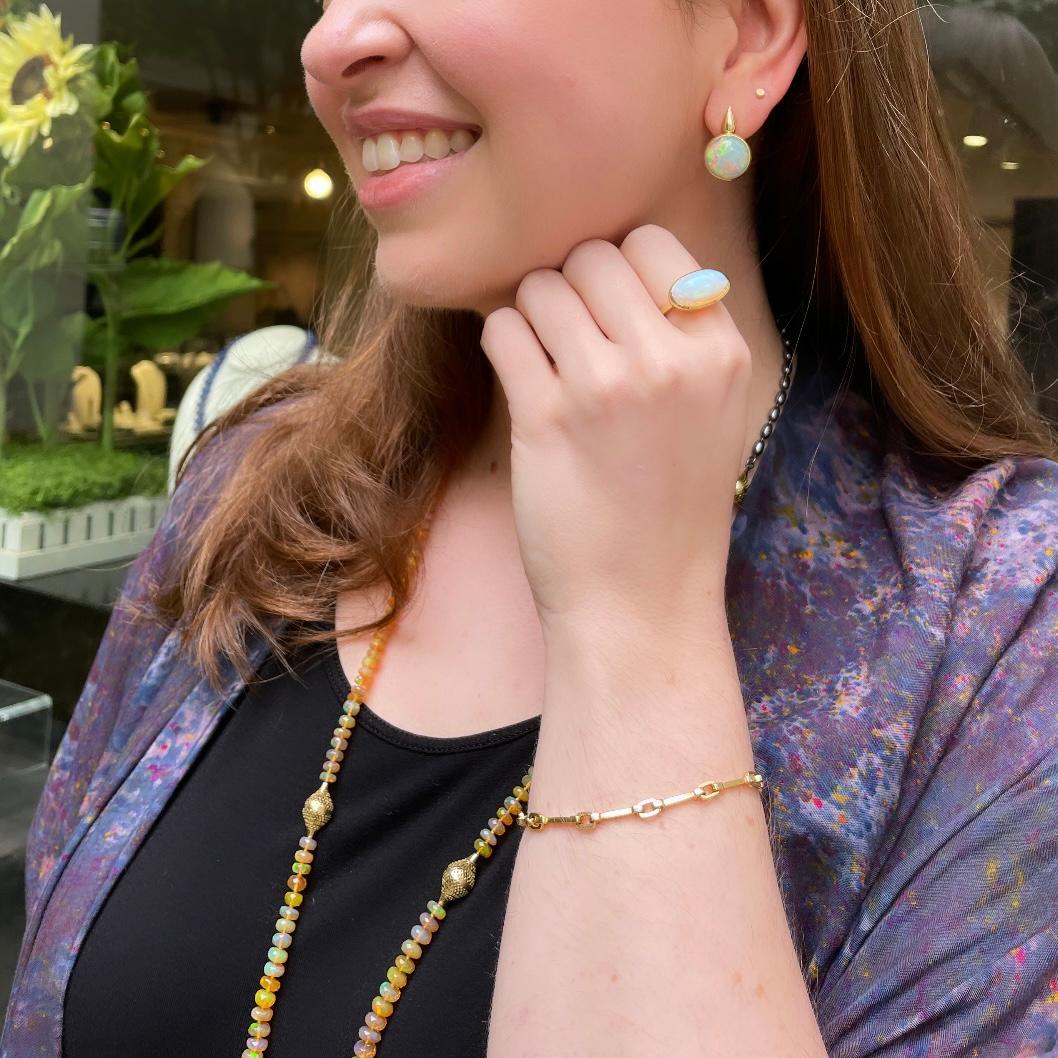 photo of a woman wearing opal earrings, ring, and necklace. And a gold bracelet.