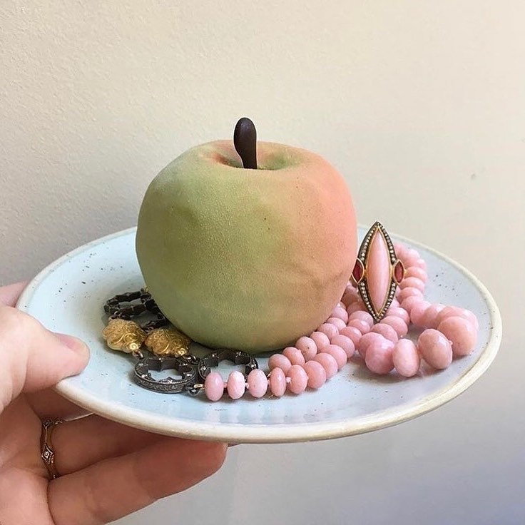 Jewelry on a plate surrounding a pastry made to look like an apple