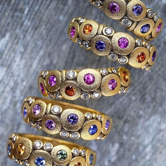 stack of yellow gold rings with multicolored sapphire and diamonds