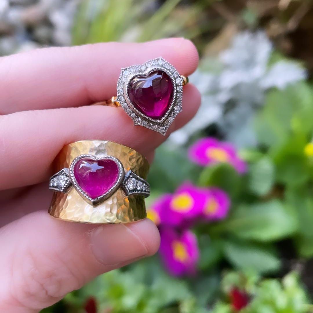 antique looking ring with pink tourmaline heart shape stones being held on a green background