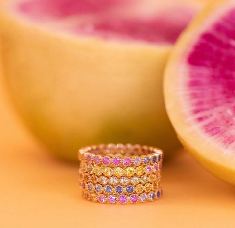 yellow and pink background with stack of rainbow sapphire rings