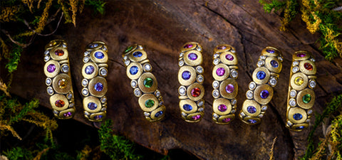 multicolored rings in yellow gold on woodsy background