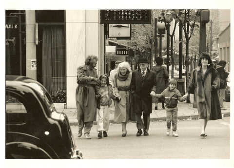 BLack and white photo of 3 generations of a family walking across a street