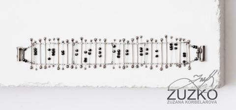 Sterling Silver Zuzko bracelet with black beads on a white block with "Zuzko" and a signature in the bottom right hand corner