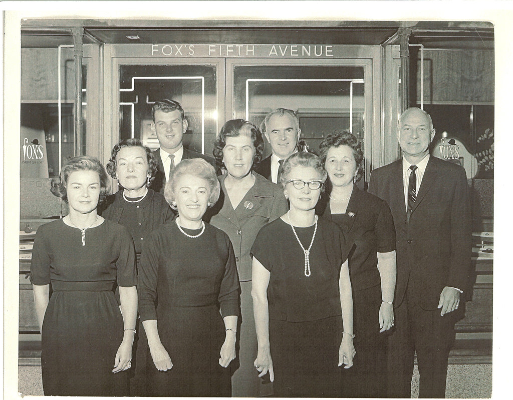 black and white photo of Fox's staff in the 1950s. 6 women and 3 men. Above the door it says "Fox's Fifth Avenue"
