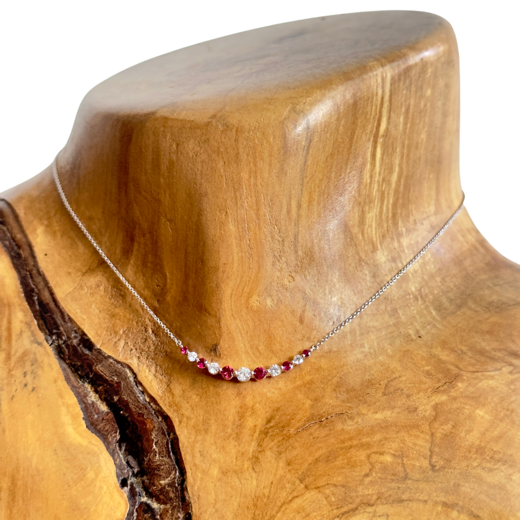 18k white gold ruby and diamond necklace pictured on a wooden neck
