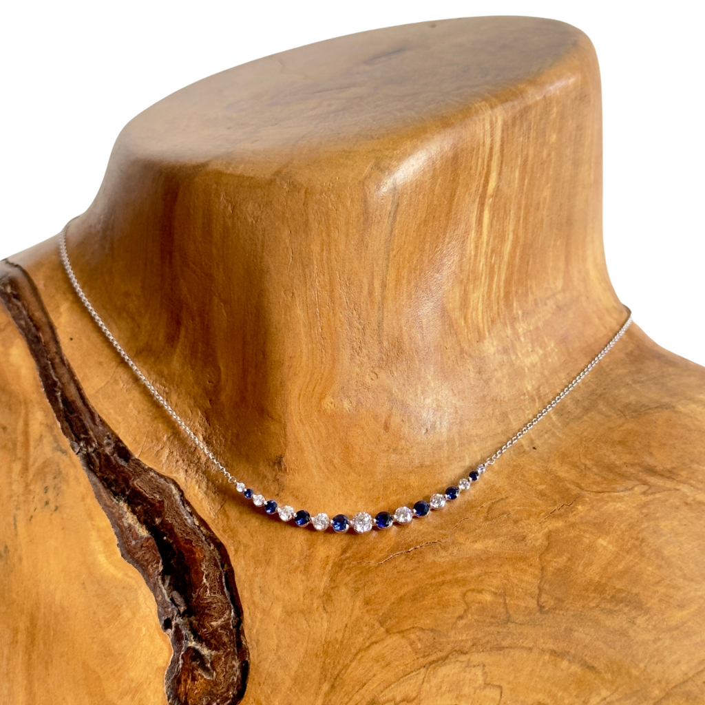 18k white gold sapphire and diamond necklace pictured on a wooden neck
