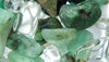 Close up of green and clear gemstones in water bottle