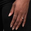 Two thin ILA diamond rings on a hand, one pear cut yellow gold ring and one lined with pave diamonds