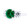 Bayco Jewels platinum ring centering a round 2.42 carat Zambian emerald flanked by round brilliant cut colorless diamonds, side view