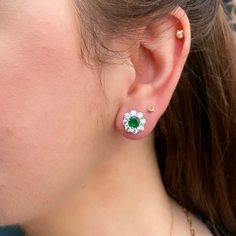 Bayco Jewels Platinum earrings featuring a pair of round Sandawana emeralds, each set within a round colorless diamond surround for pierced ears on model
