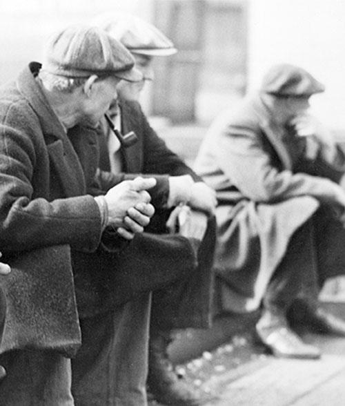 Three men sitting on a street corner.