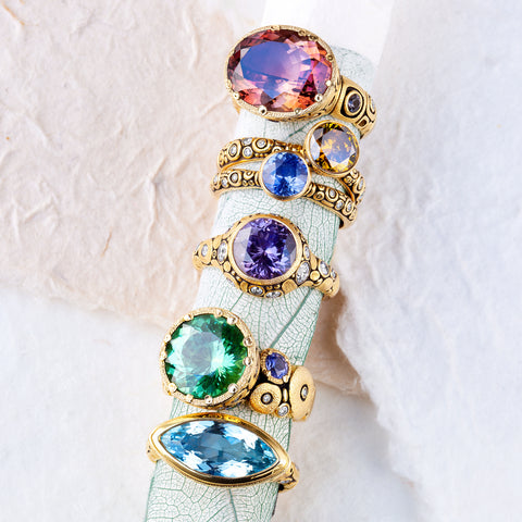 Alex Sepkus colored stone rings on white textured background.