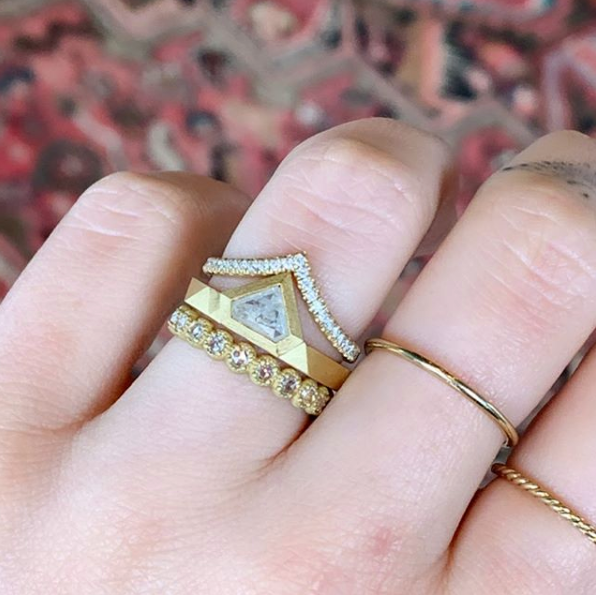 Woman's hand wearing Samantha Louise 18KY tracer band with diamond all along the rim. Hand also wearing four other Samatha Louise bands.