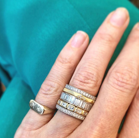 Woman's hand wearing 18K yellow gold thin Geo band with pave set diamonds. Hand also wearing five other mixed metal rings.